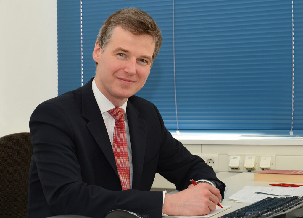 Porträfoto von Professor Marcus Stiemer am Schreibtisch